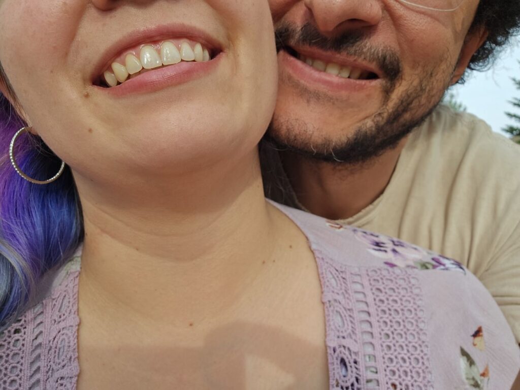 Partial faces of a human couple trying to smile while the sun is in their eyes.
