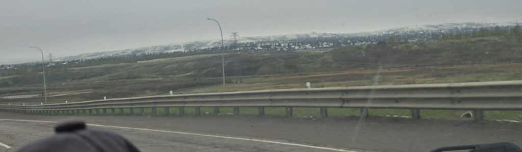A large snowy hillside in a Canadian city viewed from an Albertan highway.