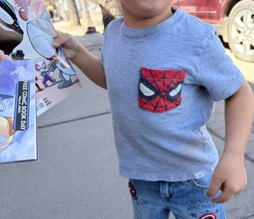 A toddler in Spider-Man shirt holding a Spidey And His Amazing Friends comic book