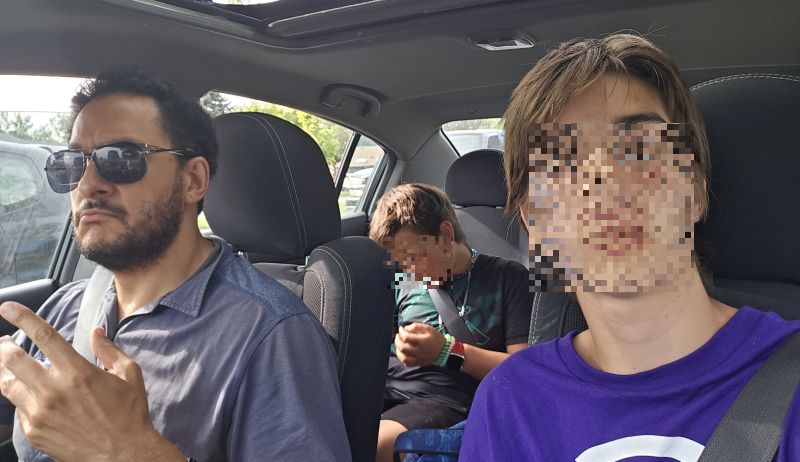 A crew of adult and youth miscreants in a car on the way from somewhere to somewhere.